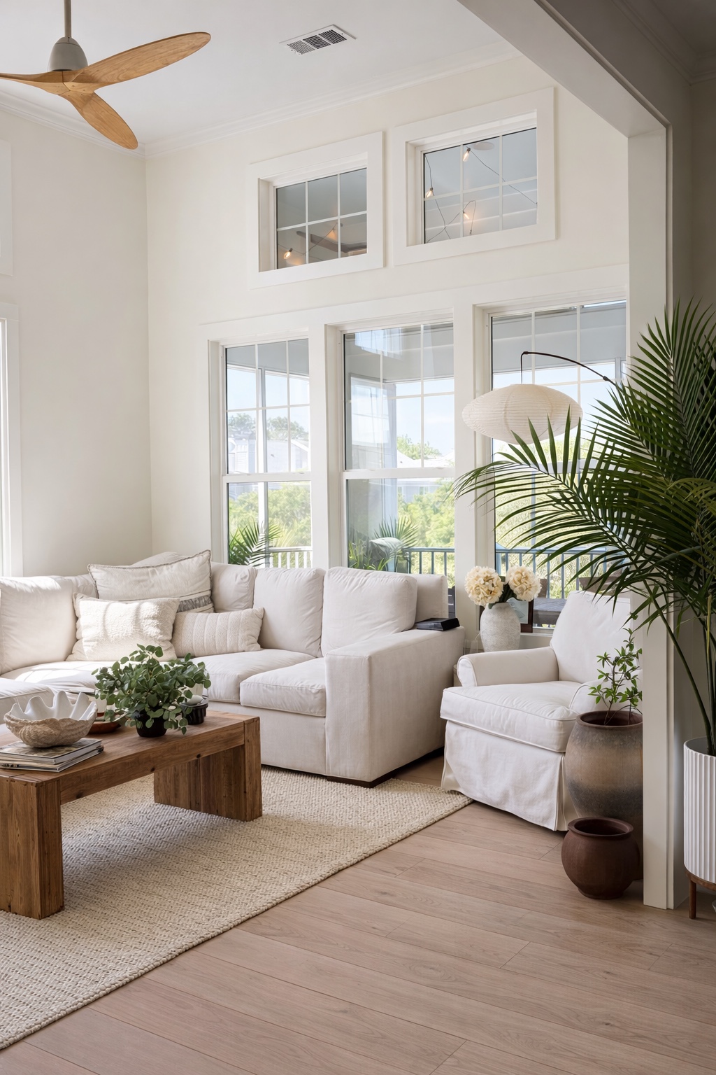 Bright living room with soft neutral furnishings, wood accents, and airy windows.